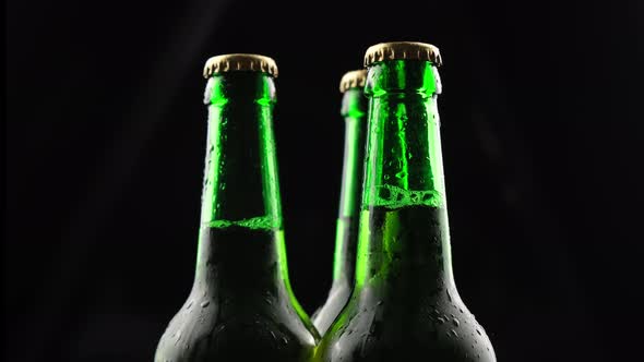 Three Green Glass Beer Bottles Spinning on a Black Background in the Dark alt