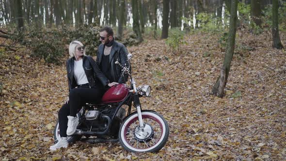 Portrait of Stylish Couple in Love Looks on Each Other and Smiles in Park alt
