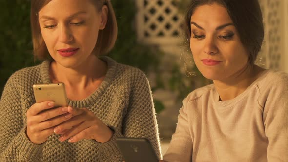 Women Looking at Social Network Page of Their Friends, Discussing Rumors Closeup alt