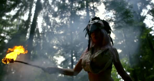 Mysterious Witch with Mask on Head Carries Torch with Fire alt