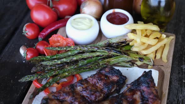 Delicious Beef or Pork Grilled Ribs Served with Aspargus and French Fries on a Wooden Board alt