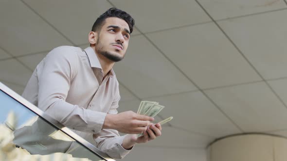 Bottom View Young Pensive Successful Bearded Guy Rich Business Man Holding Bundle of Money Banknotes alt
