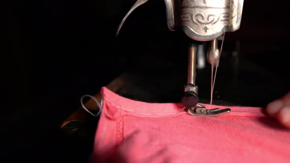 A Seamstress Sews Red Fabric On An Antique Sewing Machine