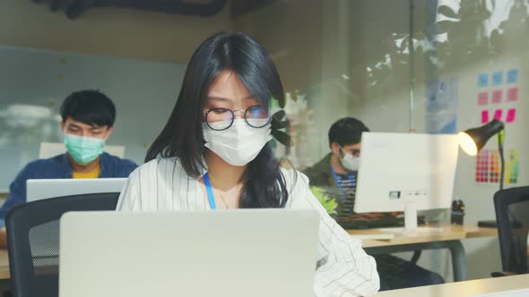asian female adult wearing protective face mask working with laptop