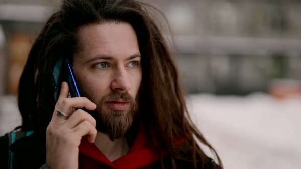 A Portrait of an Attractive Handsome Man with a Beautiful Hairstyle and Beard is Talking on the alt