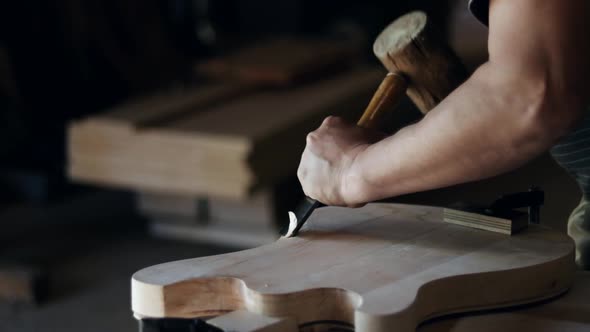 Craftsman forms a guitar in the shape of a wooden board