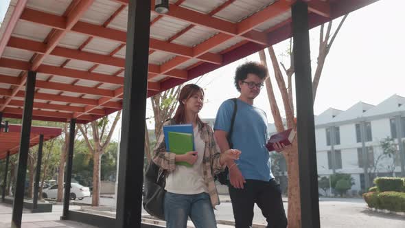 Happy Asian students walking and talking on walkway of university. Education and student concept