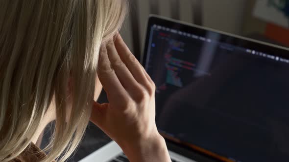 Woman developer coding on laptop computer with headache