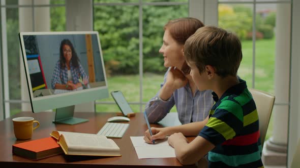 Young 30s Mother Helping Her Son with Online Lesson at Home alt