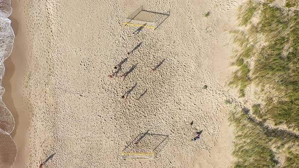 AERIAL: Group Plays Football on Sand on a Beach on Sunny Day