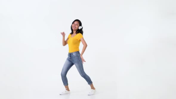 Portrait of happy carefree asian young woman dancing while listening to music