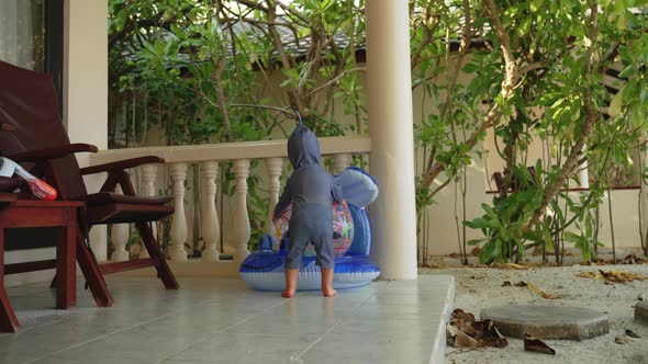 A Child Plays with Rubber Inflatable Toys on the Beach Outside the Room alt