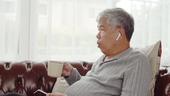 Senior man use wireless earphone listening music and talking telephone alt