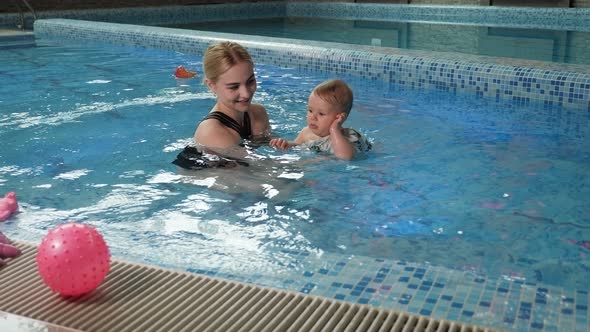 Young Cheerful Mother and Little Daughter Enjoying Swimming in a Swimming Pool alt