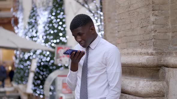 young black businessman enter the number on the mobile and speaking hand free alt