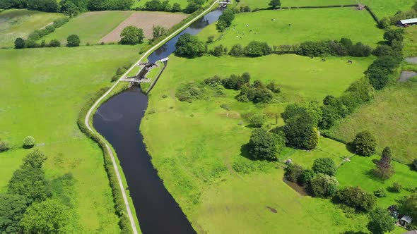 Aerial view over an English canal going through a green countryside setting alt