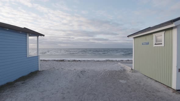 Small cabins by beach cold spring day with iced ocean. Floating gimbal camera forwardement. Eternal alt