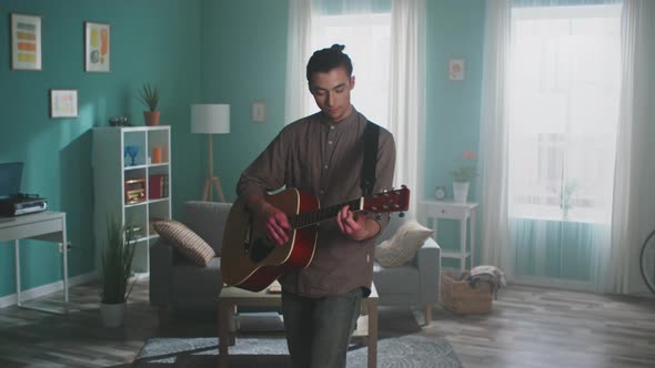 Young Man Is Playing Guitar at Home alt