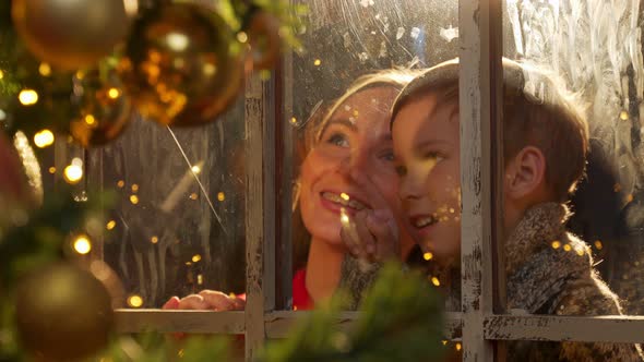 Young Mother and Son Look Out the Window at the Christmas Tree alt