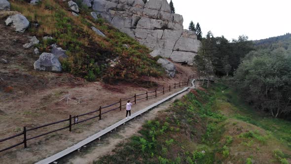 Aerial Top View of Young Tourist Woman Walking on Wooden Trail Between Rocks in National Park of alt