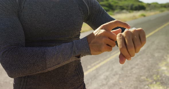 Triathlete man using smartwatch on a sunny day alt