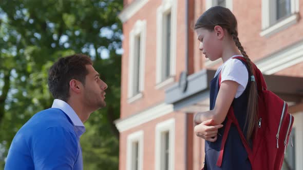 Side View of Father Cheering Upset Daughter Outside School Building alt