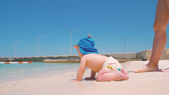 For the First Time, a Child Near the Ocean with His Mother Touches Salt Water  alt