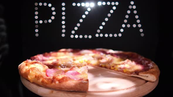 Delicious  Fresh Italian Pizza On A Black Background With The Effect Of Light Inscription Pizza