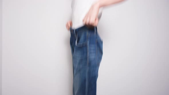 Happy Woman Dancing in Oversized Jeans on White Background