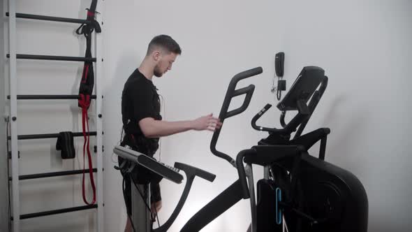 Bearded Man in Ems Suit Turns on the Electric Stimulation and Starts Working Out alt