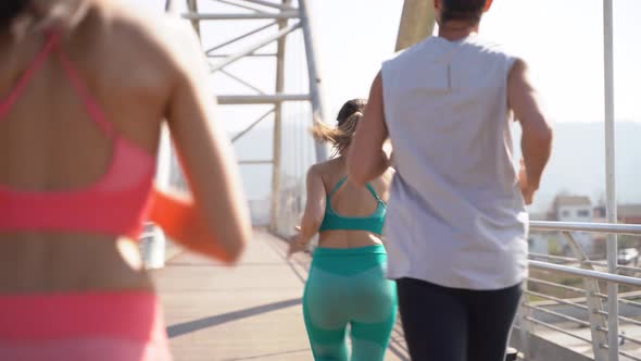 Group of friends jogging on bridge alt