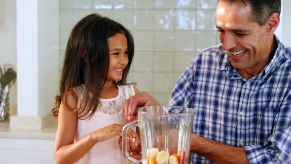 Father and daughter preparing smoothie in kitchen alt