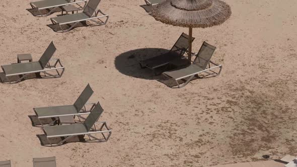Empty Beach with Thatched Sunshades and Sunbeds on Sunny Day