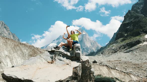 Loving Family Young Couple of Tourists Sit on a Rock and Take Pictures and Shoot Video on a alt