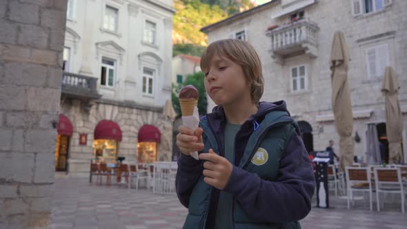 The Little Boy is Eating Chocolate Ice Cream Standing on a Square in the Old Town of Kotor in alt