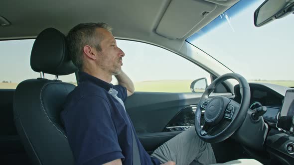 Male driver sitting in an autonomous car, letting the car drive by itself alt