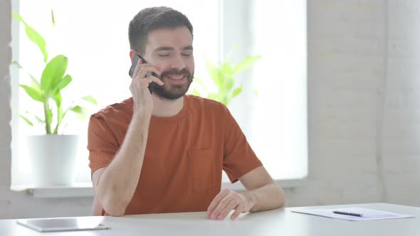 Young Man Talking on Phone Discussing Work alt