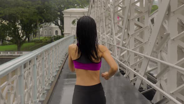 Middle-aged Asian woman jogging in the rain in Singapore  alt