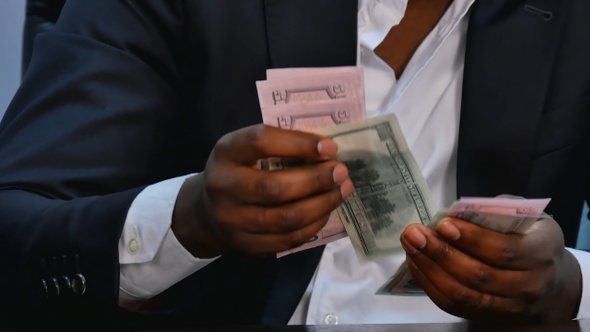Male hands counting dollar bills on wooden table