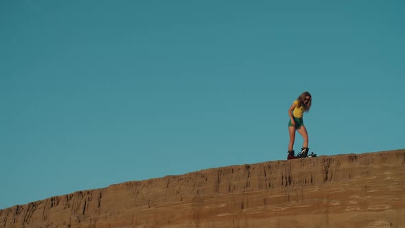 Sexy Girl Getting Ready for the Ride From the Edge of a Cliff on a Sandboard or Snowboard. Blonde alt