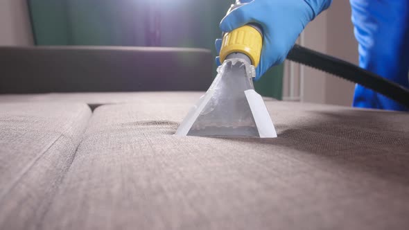 Concept of Cleaning in the Apartment and Office. Dry Cleaning Worker Removing Dirt From Sofa Indoors alt
