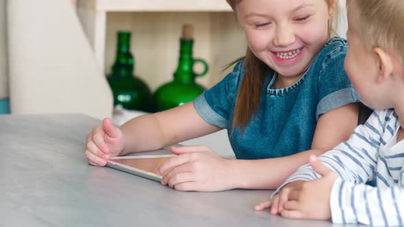 Kids Laughing and Playing on Tablet Together at Home