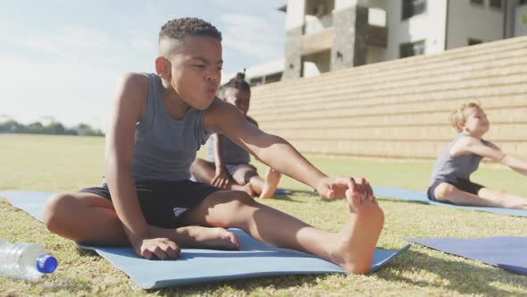 Video of focused diverse boys practicing yoga on mats on sunny day alt