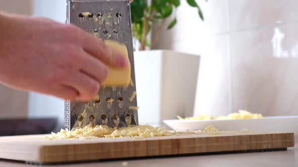 A Man Rubs Cheese on Metal Grater for Freezing and Further Cooking Pizza Pasta