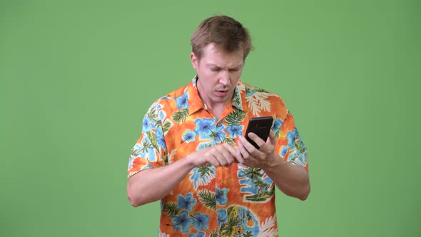 Young Handsome Tourist Man Using Phone and Giving Thumbs Down alt