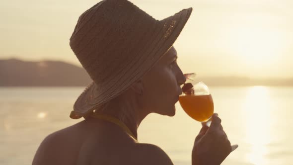 Closeup Video of a Woman Drinking a Cocktail on the Beach During Sunset alt