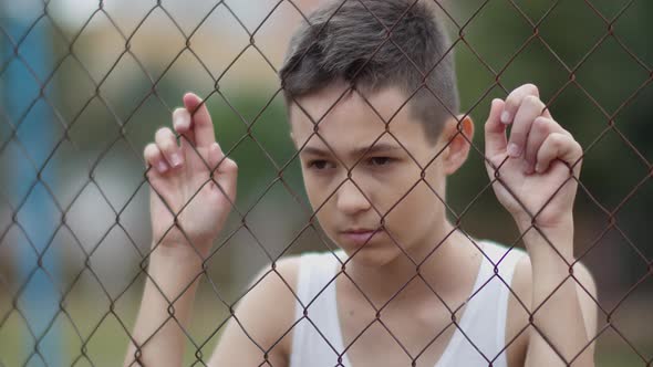 Tortured Angry Boy Refugee Serious Boy Stands Alone Head Bowed Near the Fence Regrets Actions