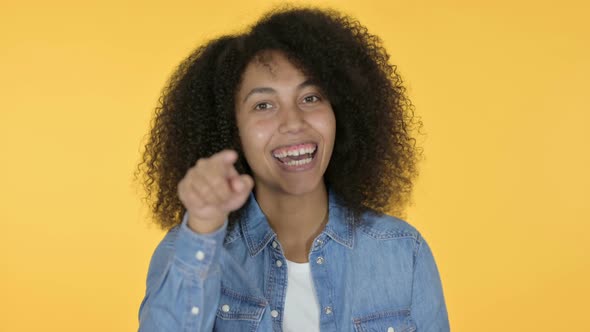 African Woman Pointing with Finger, Yellow Background  alt