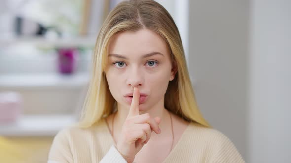 Serious Young Woman Putting Finger on Lips Showing Hush Gesture Looking at Camera alt