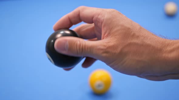 A man holds a magic billiard ball with the number 8  in his hand.